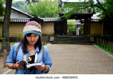 Traveler Thai Woman Reading Guide Book For Travel Nara City In Garden Of Todaiji Temple At Kansai Region In Nara, Japan