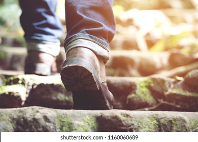 Traveler Tourist Close Up Leg Of Young Hipster Man One Person Hiker Shoe Boots Hiking. Tourist Hikers In Adventure Forest Step Trail Walking Stepping Going Up The Stairs With Sunshine. Travel Concept.