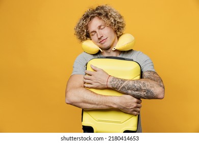 Traveler Tourist Man He Wear Grey T-shirt Sleep With Neck Pillow Hold Suitcase Bag Isolated On Plain Yellow Background Studio. Passenger Travel Abroad On Weekends Getaway. Air Flight Journey Concept