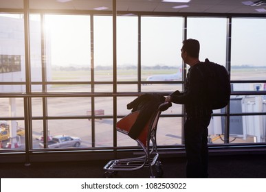 Traveler tourist man with luggage  looking at the airplanes while waiting at boarding gate before departure.travel,holiday concept.