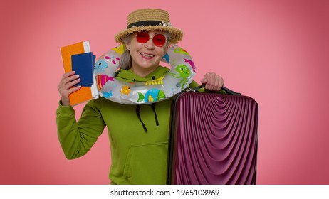 Traveler Tourist Senior Old Woman Granny Celebrating, Holding Passport, Tickets, Luggage. Concept Summer Vacation, Journey, Trip To Seaside. Isolated On Studio Pink Wall Background. Air Flight Journey