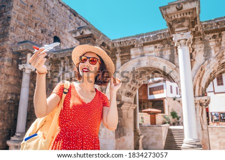 traveler with a toy plane on the background of the archaeological monument - the gate of the Emperor Hadrian in the old city of Antalya. Concept of air tickets and airlines in Turkey