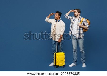 Traveler two friend men wear shirt hold bag backpack look aside far away isolated on plain dark royal navy blue background Tourist travel abroad in free spare time rest getaway Air flight trip concept