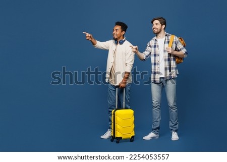 Traveler two friend men wear shirts hold bag backpack point finger aside isolated on plain dark royal navy blue background Tourist travel abroad in free spare time rest getaway Air flight trip concept