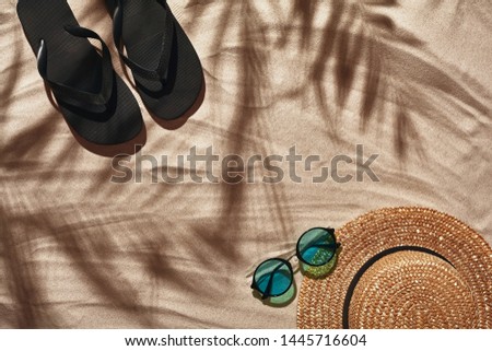 Traveler vacation accessories are laid out on a white beach sand. Flat lay, top view.