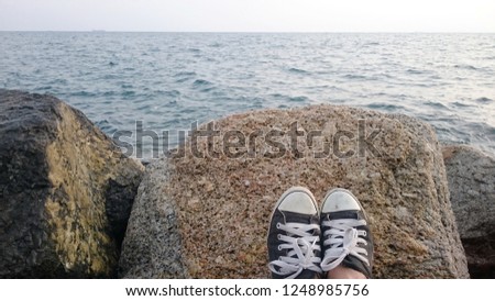 Traveler wear sneakers, put on the rock at the beach. 