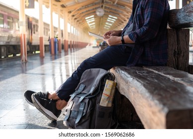 Traveler wearing backpack waiting for a train at trainstation and planing for next trip. Copyspace of travel concept.