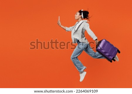 Traveler woman of African American ethnicity wear casual clothes hold bag mobile phone isolated on plain orange background Tourist travel abroad in free spare time rest getaway Air flight trip concept