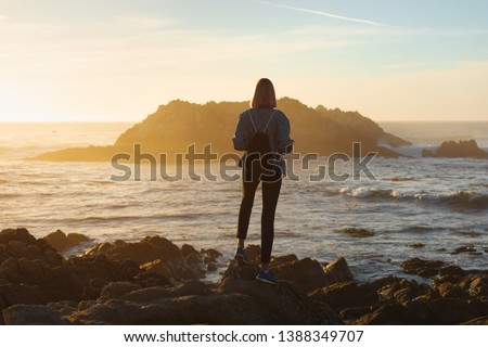 Traveler woman with backpack enjoying ocean view, girl hiker at sunset, travel concept, California, USA