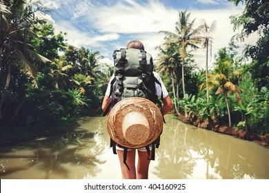 Traveler woman with backpack standing near big tropical river at sunny day