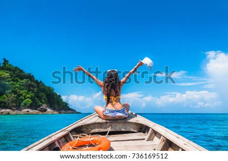 Traveler woman in bikini relaxing and enjoying on wooden boat her arms open feeling freedom, Andaman sea, Mu Koh Surin National Park, Phangnga, Travel in Thailand, Summer holiday and vacation trip