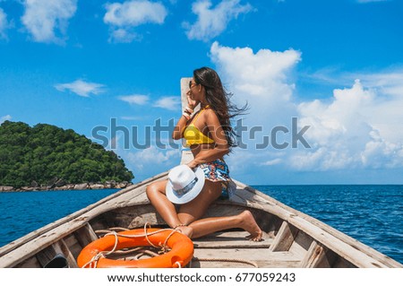 Traveler woman in bikini relaxing and sunbathe on wooden boat, Andaman sea, Mu Koh Surin national park, Phangnga, Thailand