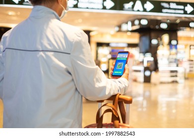 Traveler woman in duty free area in airport showing cellphone with mobile app for people vaccinated of covid-19. Immunity passport for travel - Powered by Shutterstock