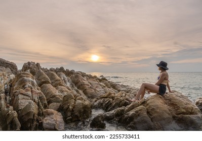 traveler woman enjoying sunset alone on rocky beach - Shutterstock ID 2255733411
