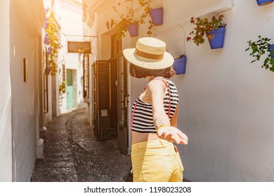 Traveler woman follow me to the famous white street with flowers in Andalusia, Spain