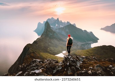 Traveler woman hiking solo in mountains of Norway outdoor activity travel summer vacations healthy lifestyle girl tourist enjoying sunset view on summit exploring Senja island - Powered by Shutterstock