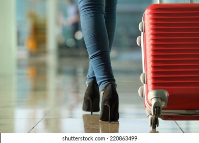 Traveler woman legs walking carrying a suitcase in an airport