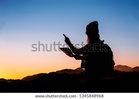 Traveler woman looking at the map with morning in mountains background.