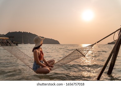 Traveler Woman Relax On Hammock In The Sea Between Sunset At The Beach