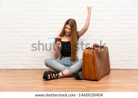 Traveler woman with suitcase and boarding pass celebrating a victory