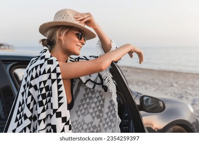 Traveler woman taking a break  by her car on a pebble beach. - Powered by Shutterstock