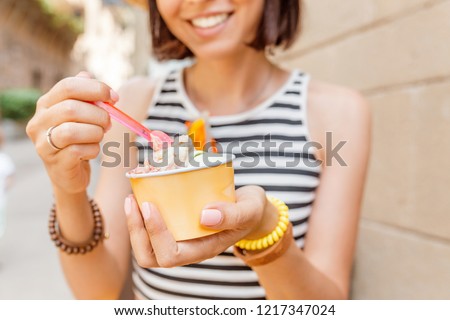 Traveler woman is trying ice cream wearing a straw hat in the city