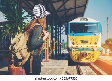 Traveler woman walking and waits train on railway platform