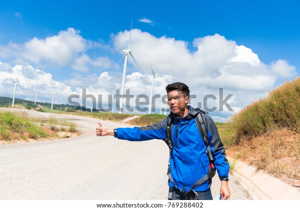 Traveler \
young man and backpackers waiting car and Freedom traveler man\
standing with raised arms at the\
roadside.