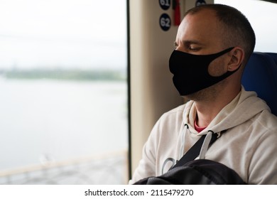 Traveler young man in a protective mask sleeps on the train by the window. Close-up. Copy space.