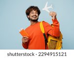 Traveler young teen boy student man wear casual clothes backpack bag hold passport ticket mock up of plane isolated on plain blue background. Tourist travel abroad to study. Air flight trip concept