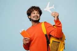 Traveler Young Teen Boy Student Man Wear Casual Clothes Backpack Bag Hold Passport Ticket Mock Up Of Plane Isolated On Plain Blue Background. Tourist Travel Abroad To Study. Air Flight Trip Concept