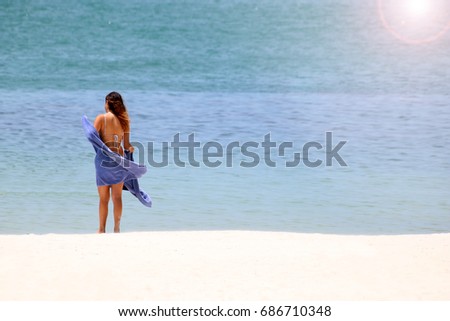 Travelers girl with a towel on the white sand beach. 
