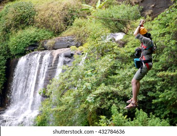 Travelers hung on a a wire rope over a vast forest, a fun and challenging activity, a zipline in bolaven plateau southern laos, hung over waterfall - Powered by Shutterstock