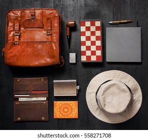 Traveler's set ready for vacation. Leather bag, flask for brandy, lighter, sun glasses, paper notebook, pen, chess board, hat and smoking pipe. - Powered by Shutterstock