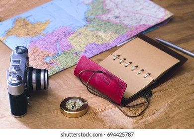 Traveler's things: camera, map, notebook, compass on a wooden background