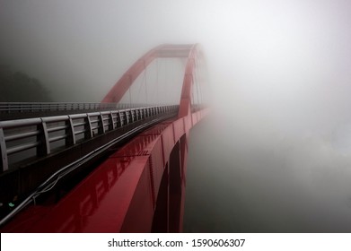 
Traveling around the island of Taiwan in Asia. View from the road to a totally hazy  modern metal red bridge and dangerous situation on the road. Foggy path, no visibility over the gulf on the road.
