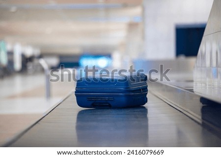 Traveling by airplane. Selective focus on lonely blue suitcase on baggage claim in airport terminal.
