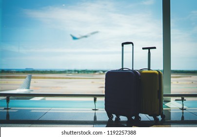 Traveling by airplane. Two suitcases in airport departure lounge, vacation concept or business travel, airplane taking off on the background, luggage in waiting area airport terminal - Shutterstock ID 1192257388