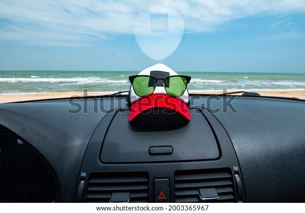 Traveling by car\
concept with sea view through the car windshield. Cap and glasses\
lie on the car\
dashboard.