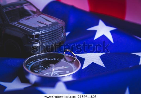 Traveling by car in\
the USA. Moving to America. Tourists by car. American roads.\
Compass, maps and usa\
flag.