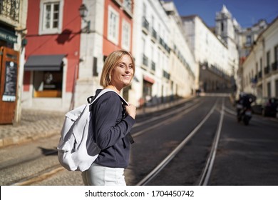 Reise durch Portugal. Fröhliche junge Frau mit Rucksack auf den Straßen von Lissabon.