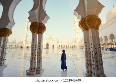 Traveling by Unated Arabic Emirates. Woman in traditional abaya standing in the Sheikh Zayed Grand Mosque, famous Abu Dhabi sightseeing.