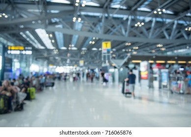 Traveling concept. Travelers asian walking with a luggage at airport terminal and airport terminal blurred crowd of Travelling people on the Background.