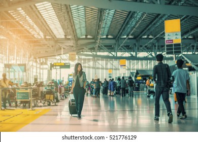 Traveling Concept. Travelers Asian Woman Walking With A Luggage At Airport Terminal And Airport Terminal Blurred Crowd Of Travelling People On The Background. (vintage Color Tone, Advertise Concept) 
