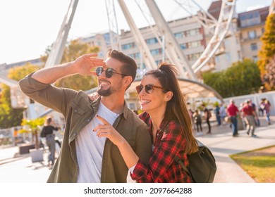 A traveling couple looking at a Ferris wheel on a sunny summer day..