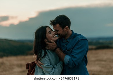 Traveling couple standing outdoors together and laughing during an evening in the hills - Powered by Shutterstock