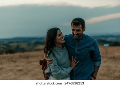 Traveling couple standing outdoors together and laughing during an evening in the hills - Powered by Shutterstock