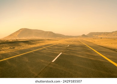 Traveling on asphalt highway road among desert during sand storm at sunset. Saudi Arabia.  - Powered by Shutterstock