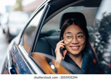 Traveling on a back seat of a car and talking on smart phone. Woman looking through rolled down window of a car. - Powered by Shutterstock