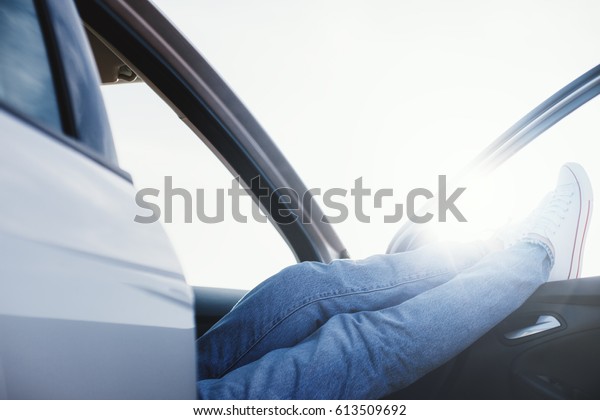 Traveling woman resting in\
the car with shoes in the window. Intentional overexposed and lens\
flares
